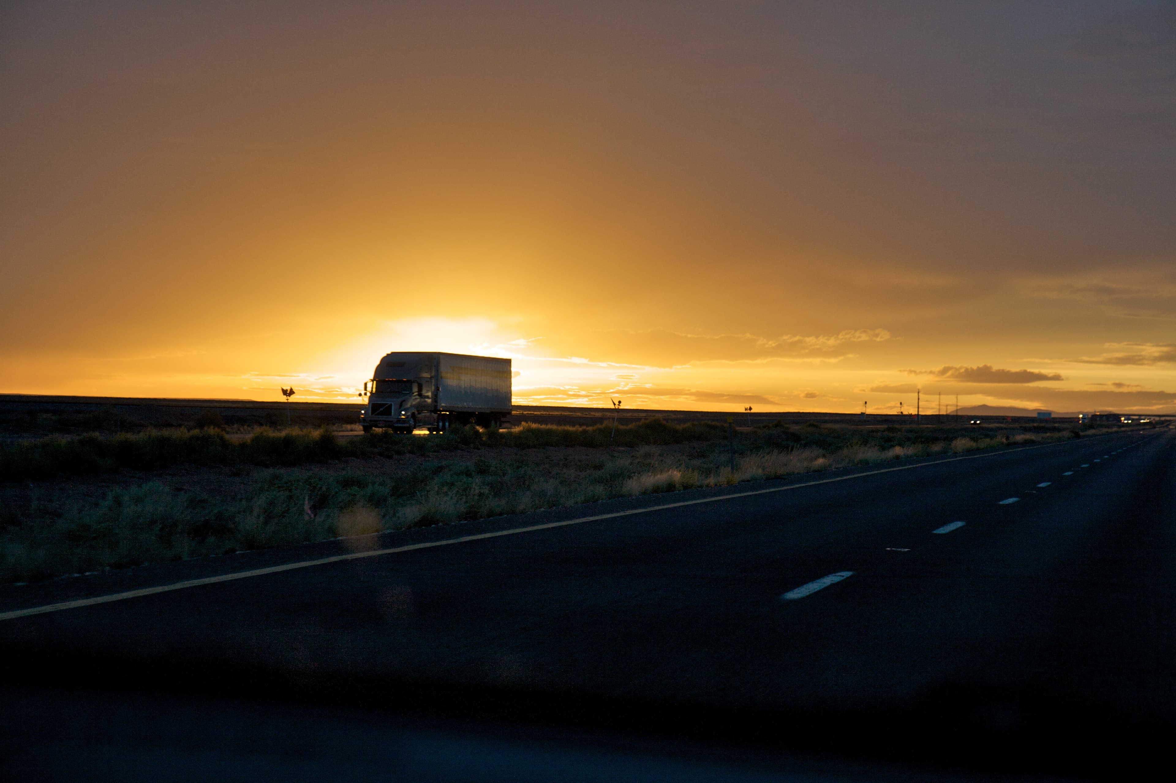 Truck rolling down the highway into the sunset